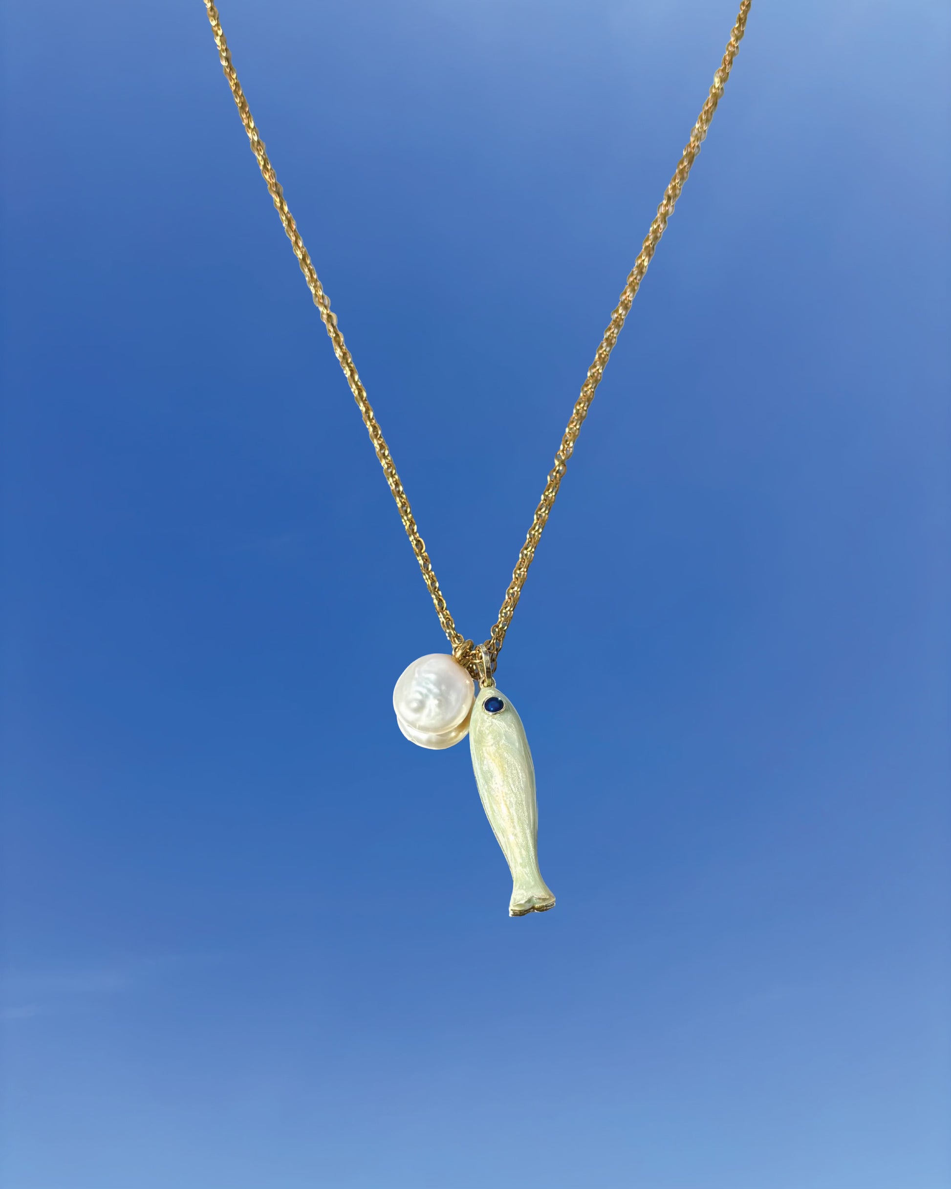 手作飾品品牌 Silhouette Spark 珍珠魚形吊墜項鍊 CLOE necklace，金色鍊條搭配白色陶瓷魚吊墜與珍珠圓珠，藍天背景