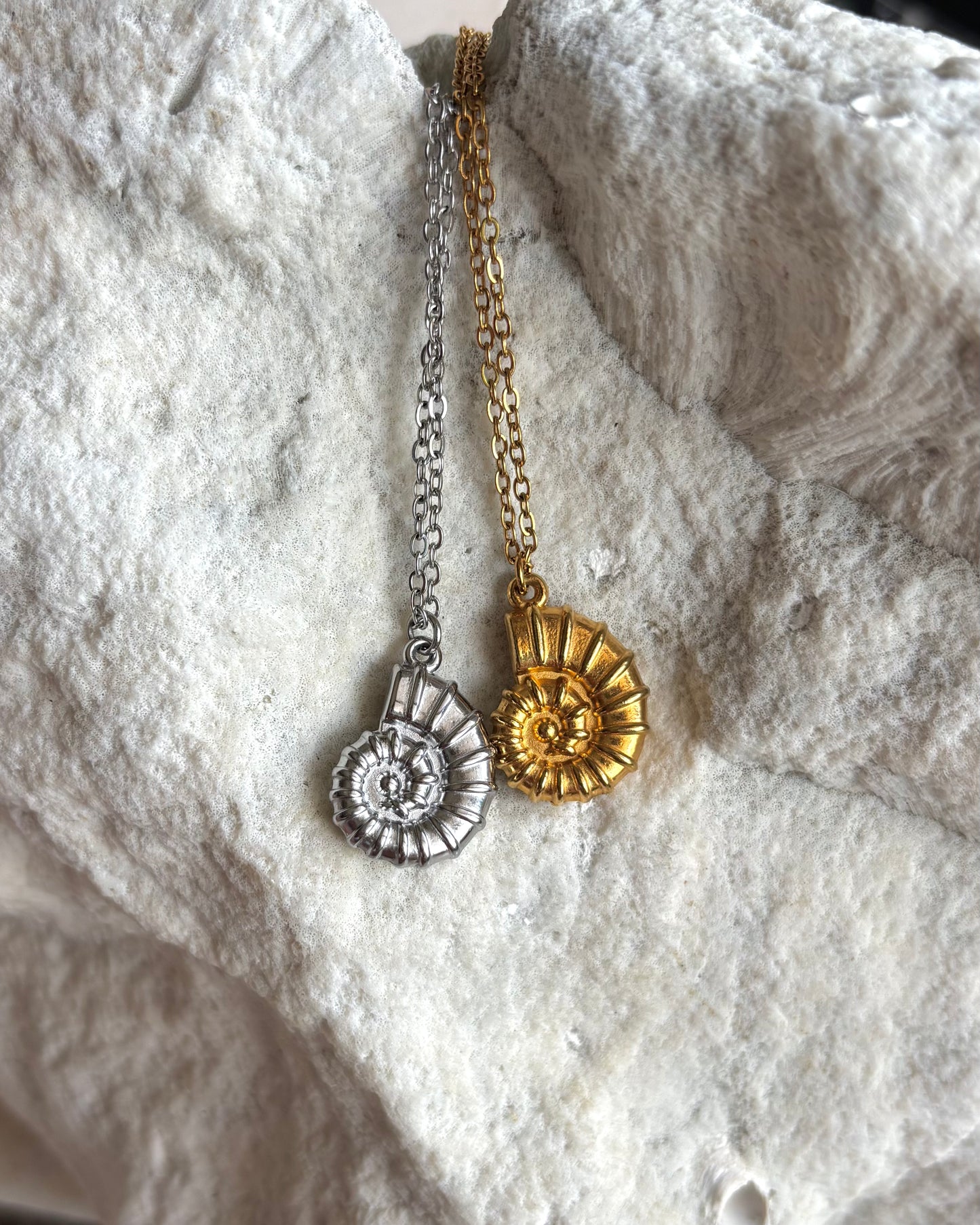 Silhouette Spark KAIA necklace 金銀雙色對比，鸚鵡螺貝殼吊墜項鍊平放於白色石材背景