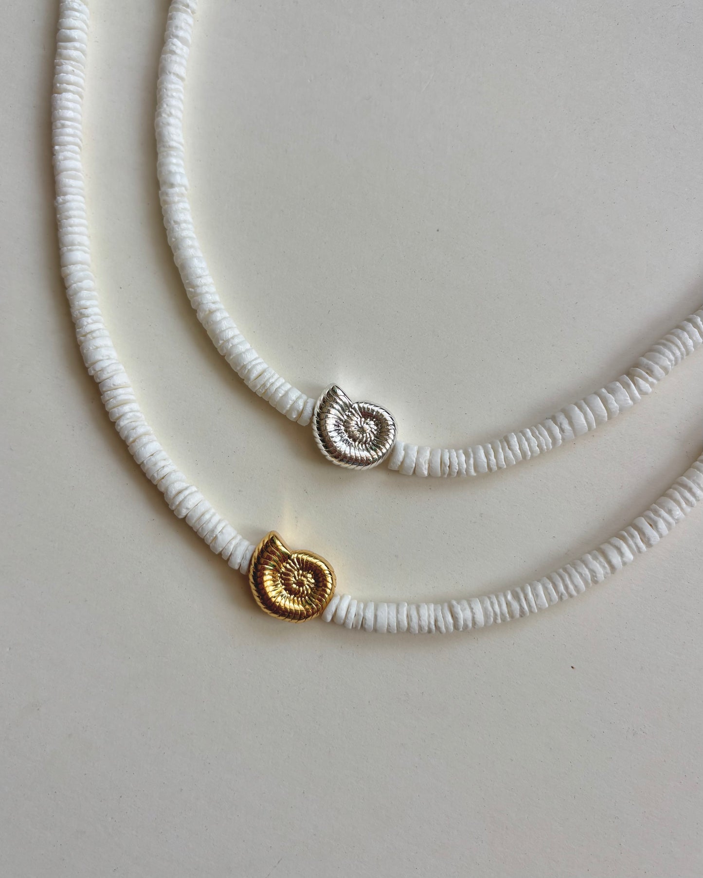 Silhouette Spark LA MER necklace 金銀雙色對比平拍，白色圓片串珠搭配鸚鵡螺吊墜，白色大理石背景