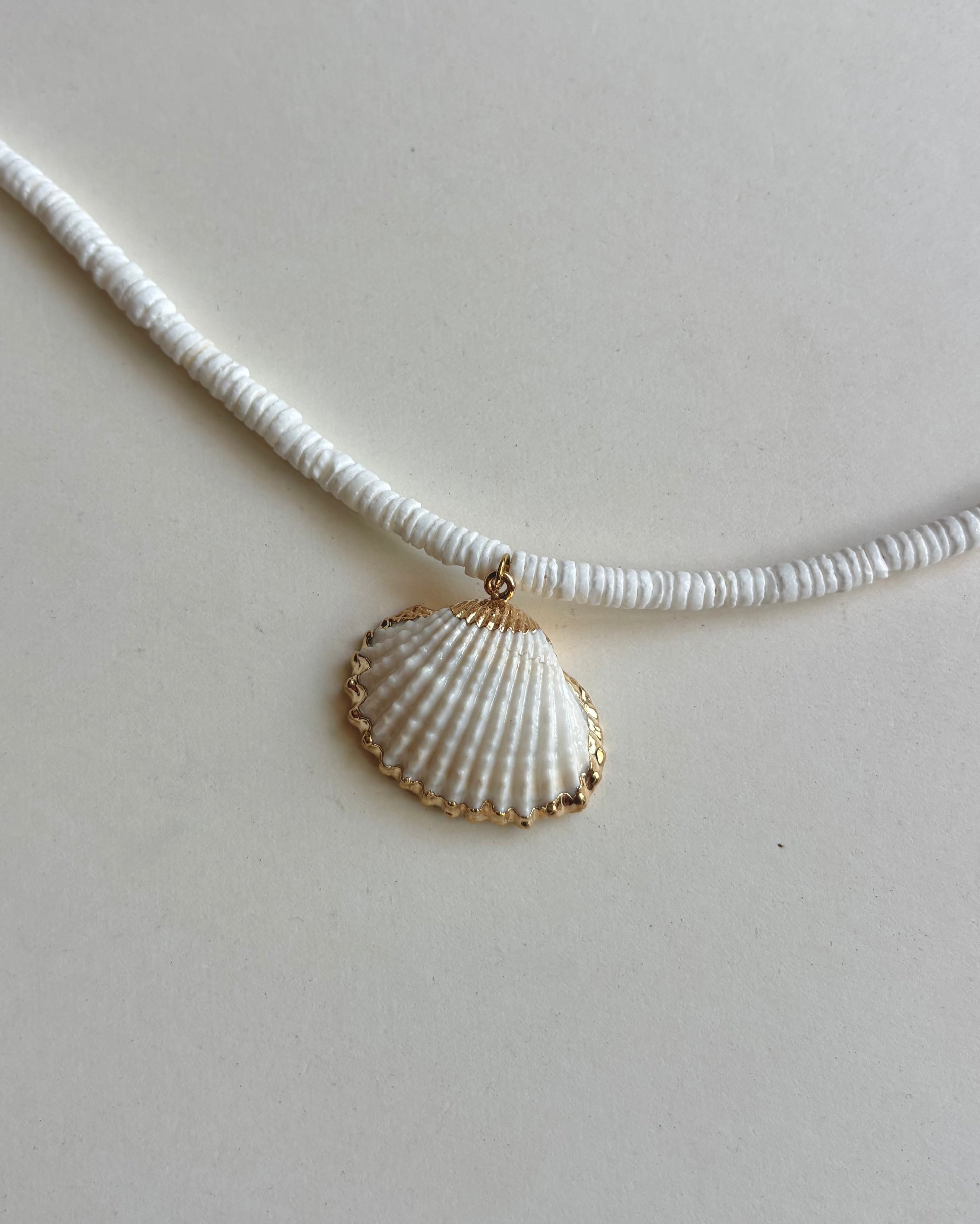 Silhouette Spark SARI necklace 白色扇貝吊墜金色鑲邊近距離特寫，白色圓片串珠鍊條，白色背景