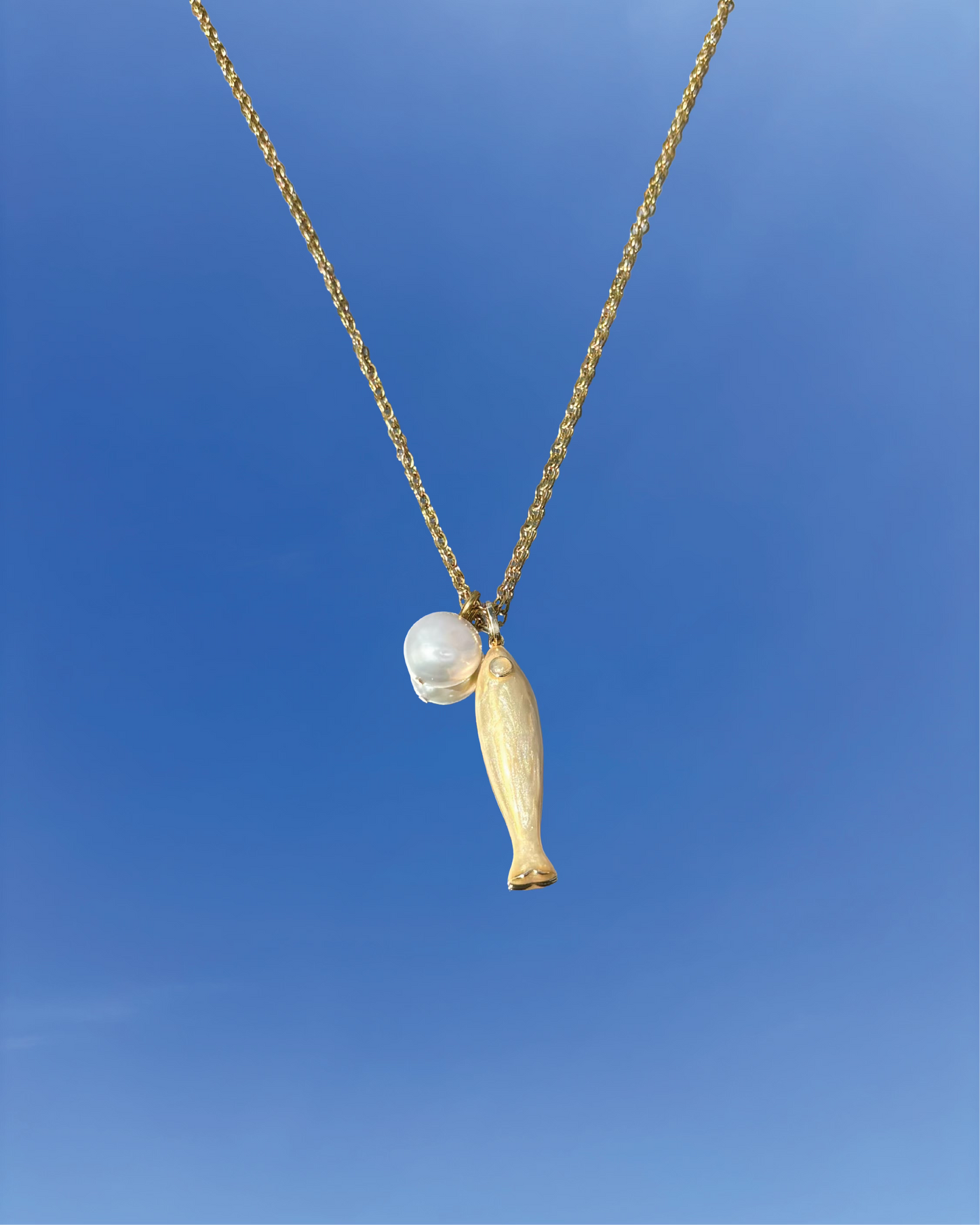 Silhouette Spark THEA necklace 金色魚形吊墜搭配珍珠圓珠項鍊，金色鍊條，藍天背景