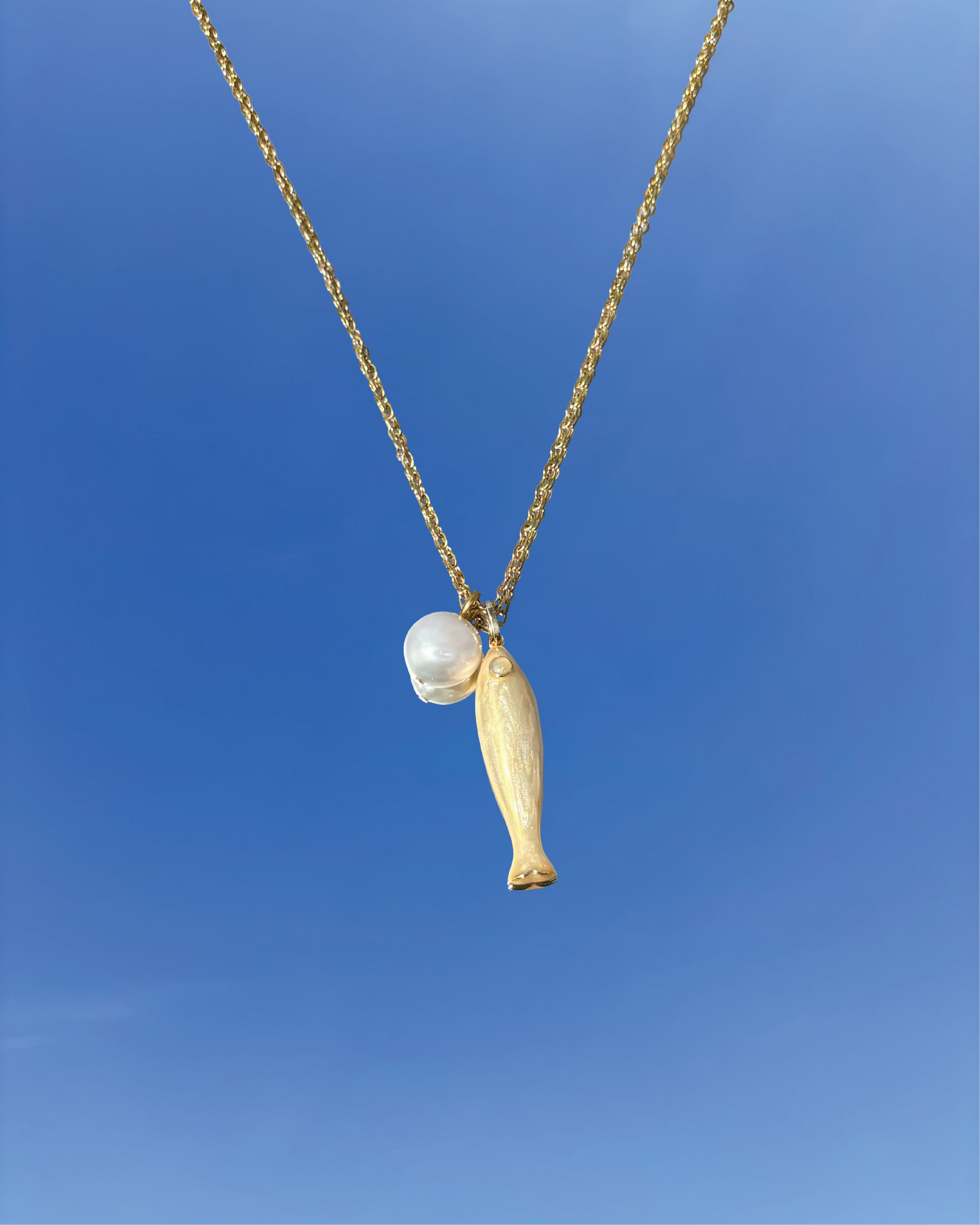 Silhouette Spark THEA necklace 金色魚形吊墜搭配珍珠圓珠項鍊，金色鍊條，藍天背景
